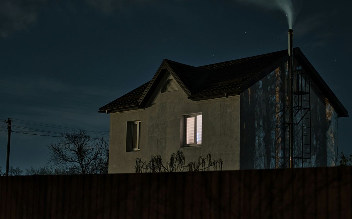 Modern house at dusk with one window lit